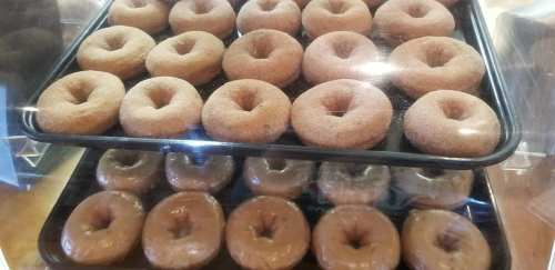 A display of two trays stacked with freshly baked chocolate donuts.