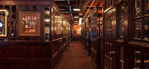 A dimly lit wooden hallway in a restaurant, featuring framed artwork and doors leading to private dining areas.