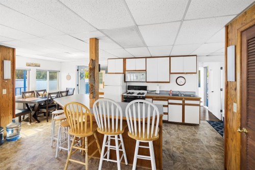 Bright kitchen and dining area with wooden accents, featuring a bar with stools and a large dining table.