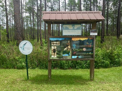 Information sign for C.L. Dees Wildlife Trail, surrounded by trees, with details about the trail and local wildlife.