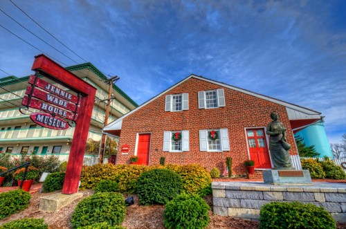Exterior of the Jennie Wade House Museum, featuring a brick building, red doors, and a statue in front.