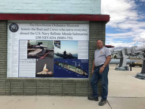 A man stands beside a display at the Hawthorne Ordnance Museum honoring the USS Nevada submarine and its crew.