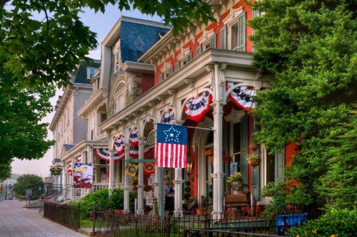 Historic homes adorned with patriotic decorations and an American flag, surrounded by lush greenery.