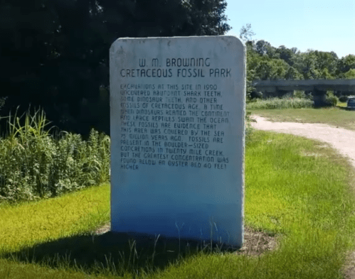 A stone monument at Cretaceous Fossil Park detailing excavations and fossil discoveries in the area.