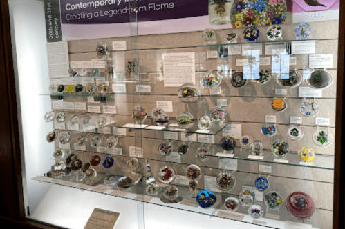 Display case featuring various colorful glass art pieces, showcasing intricate designs and craftsmanship.