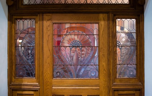 Ornate wooden door with decorative stained glass panels featuring intricate floral designs.