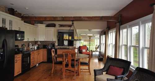 A spacious kitchen with wooden cabinets, a dining table, and large windows overlooking a scenic view.