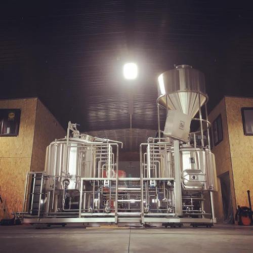 A modern brewery setup featuring stainless steel fermentation tanks and brewing equipment in a spacious industrial space.