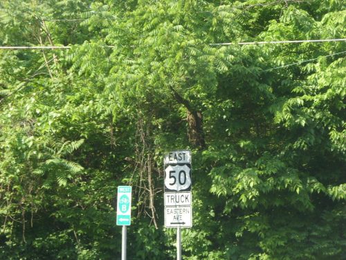 A road sign indicating East 50 Truck and Eastern Avenue, surrounded by dense green foliage.