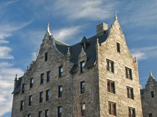 Historic stone building with ornate gables under a blue sky with wispy clouds.