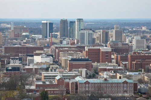 Aerial view of a city skyline featuring tall buildings and urban structures under a clear sky.