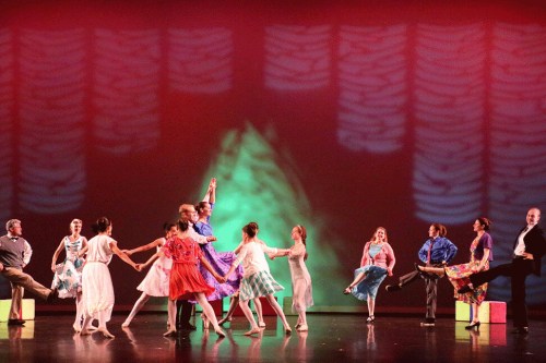 A vibrant dance performance featuring dancers in colorful costumes on stage with dynamic lighting.