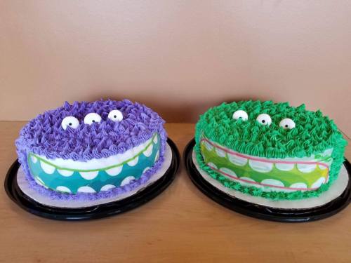 Two colorful cakes: one purple with a smiling face and one green with a playful design, both topped with white eyes.
