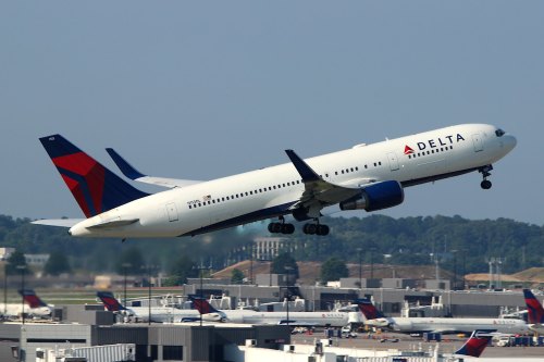 A Delta Airlines airplane taking off from an airport, with a clear blue sky in the background.