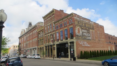 Historic brick buildings line a street, featuring a faded advertisement on the side of one building.