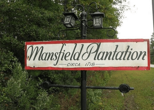 Sign for Mansfield Plantation, established circa 1718, surrounded by greenery and trees.