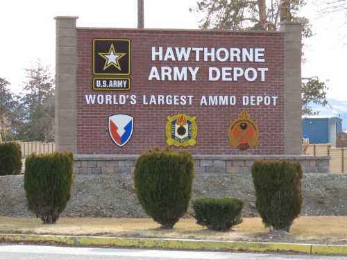 Sign for Hawthorne Army Depot, labeled as the world's largest ammo depot, featuring military insignia and landscaping.