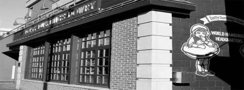 Black and white image of a restaurant exterior with a cartoon character sign and large windows.