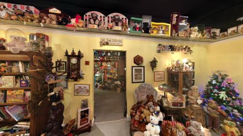 A cozy room filled with shelves of stuffed animals, toys, and vintage decor, with a doorway leading to another space.