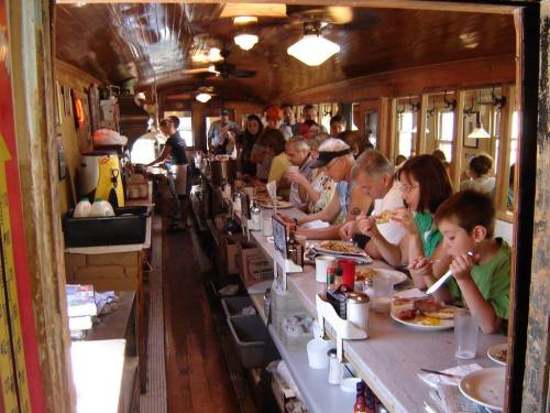 A busy diner inside a vintage train car, with patrons enjoying meals at a long counter.