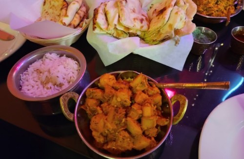 A vibrant spread of Indian cuisine featuring rice, a curry dish, naan bread, and assorted side dishes.