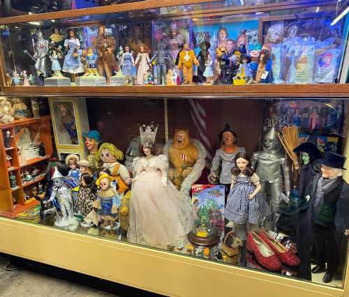 A display case filled with various dolls and figurines from "The Wizard of Oz" and other classic characters.