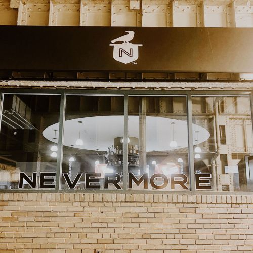 A storefront with the word "NEVERMORE" displayed prominently beneath a logo featuring a bird.