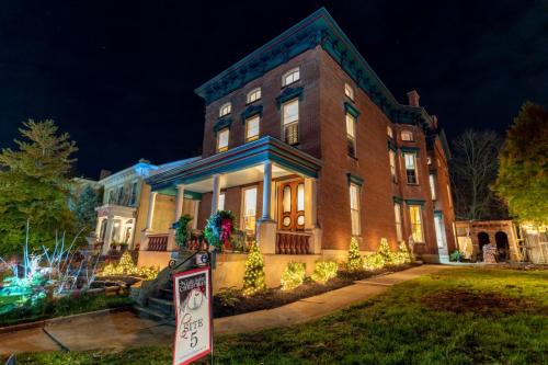 A beautifully lit historic mansion at night, adorned with holiday decorations and surrounded by greenery.
