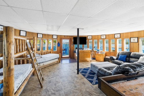 Cozy interior of a cabin with bunk beds, a sofa, and large windows overlooking a lake.