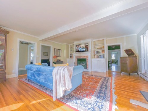 Cozy living room with a blue sofa, wooden floors, a fireplace, and a TV displaying Disney content. Bright and inviting space.
