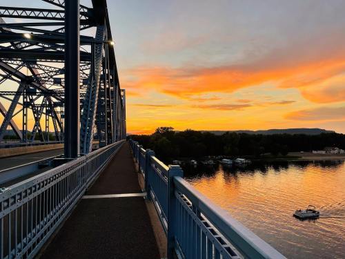 A bridge at sunset, with vibrant orange and purple skies reflecting on the water below.