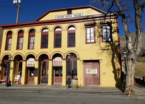 Historic yellow building with red trim, featuring arched windows and a sign for Piper's Opera House.