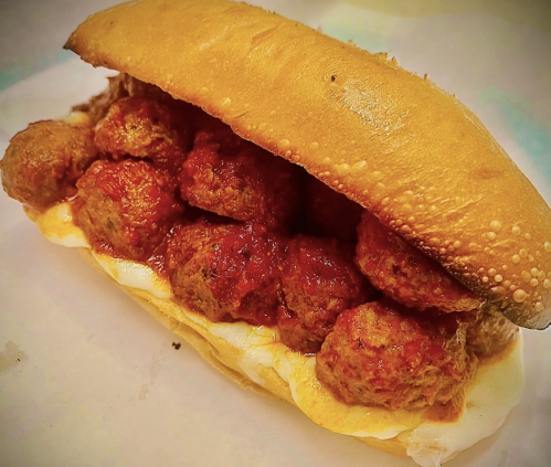 A close-up of a meatball sub sandwich filled with meatballs and marinara sauce on a toasted bun.
