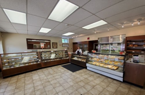 A cozy bakery interior with display cases filled with pastries and a staff member behind the counter.