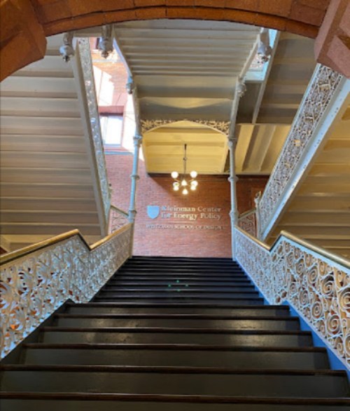Staircase with ornate railings leading to a sign for the Kleinman Center for Energy Policy.