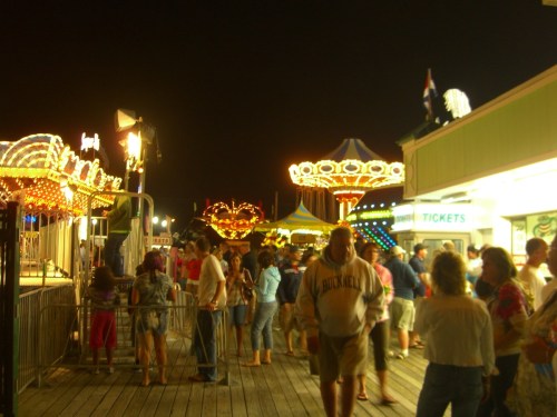 A lively night scene at a carnival with colorful lights, rides, and crowds of people enjoying the festivities.