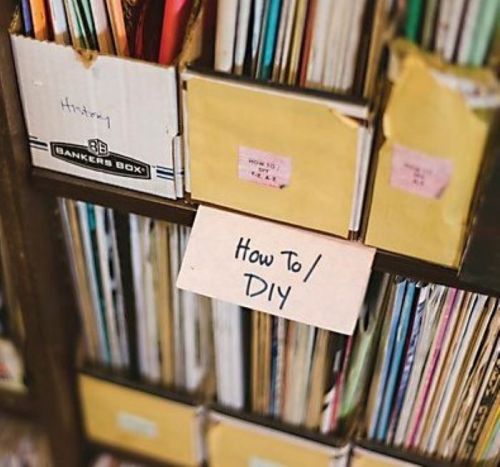 A close-up of a shelf with labeled boxes and folders, including one marked "How To / DIY."
