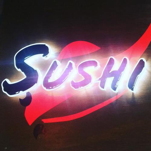 Neon sign displaying the word "Sushi" with a red wave design in the background.