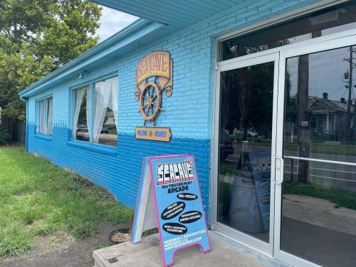 A bright blue building with a sign reading "Sea Cave" and an arcade advertisement outside.