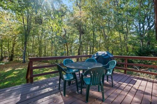 A wooden deck with a round table and chairs, surrounded by trees in a sunny outdoor setting.