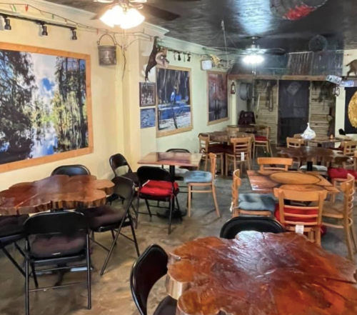 Cozy interior of a cafe with wooden tables, chairs, and nature-themed wall art.