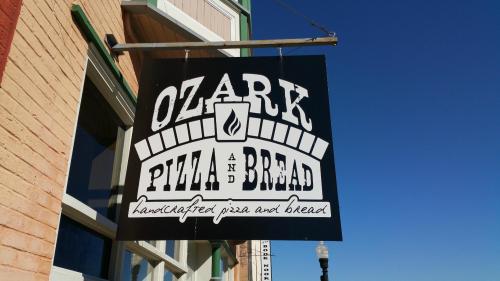 Sign for Ozark Pizza and Bread, featuring the text "handcrafted pizza and bread" against a blue sky.