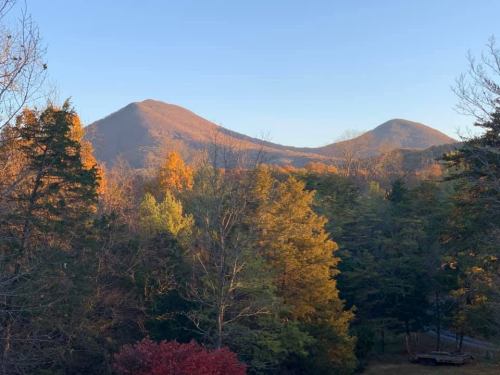 Two mountains rise in the background, surrounded by colorful autumn trees under a clear blue sky.