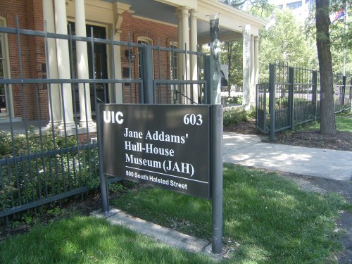 Sign for Jane Addams' Hull-House Museum at UIC, located at 800 South Halsted Street, surrounded by greenery.