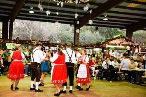 A festive gathering with people in traditional attire dancing under decorations in a lively indoor setting.