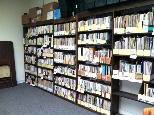 A room with wooden shelves filled with neatly organized files and boxes, creating a tidy library-like atmosphere.
