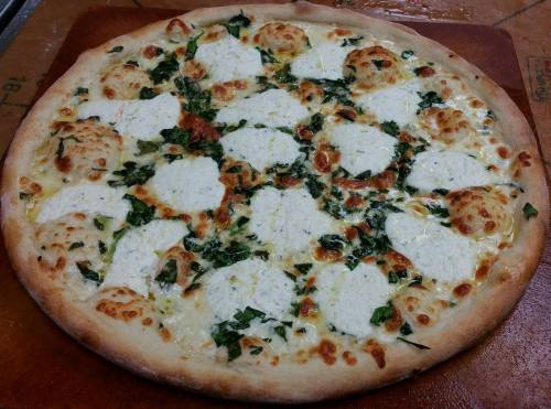 A freshly baked pizza topped with white cheese, spinach, and dollops of ricotta on a golden crust.