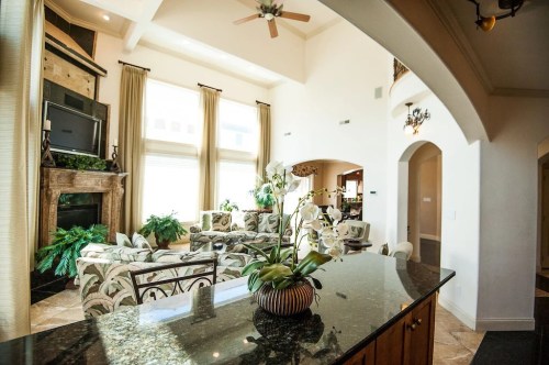 Spacious living room with high ceilings, large windows, and elegant decor, featuring a cozy seating area and plants.