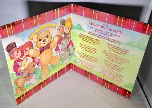A colorful children's book featuring a teddy bear and playful characters, with lyrics and illustrations on a fold-out page.
