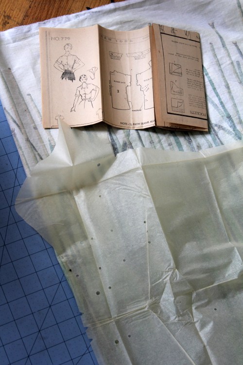 A sewing pattern and instructions laid out on fabric, with a grid cutting mat underneath.